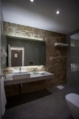 a stone bathroom with a sink and a mirror at Belomont52 Guest House in Porto