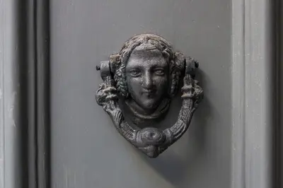 a bronze plaque of a face on a door at Studio 77 in Porto