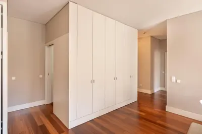 an empty living room with white cabinets and wood floors at VIVA Aliados Spacious & Bright Flat in Porto