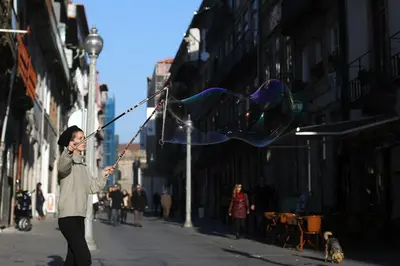 a woman flying a kite on a city street at Flores Street Apartments in Porto