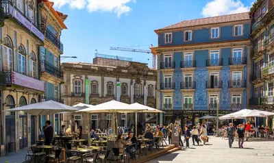 a group of people sitting at tables in a street with buildings at Flores Street Apartments in Porto