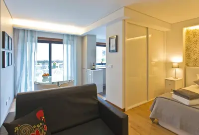 a living room with a couch and a bed and a window at I love alegria in Porto