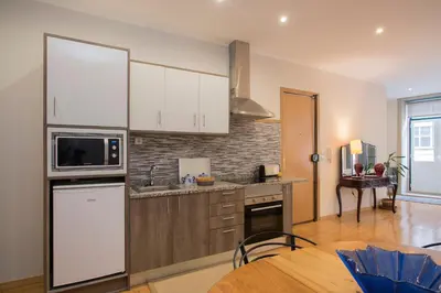 a kitchen with white cabinets and a table in it at Casa do Cristelo in Porto