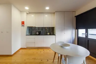 a kitchen with white cabinets and a white table at Oporto Local Studios in Porto