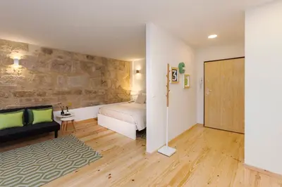 a bedroom with a bed and a stone wall at Oporto Local Studios in Porto