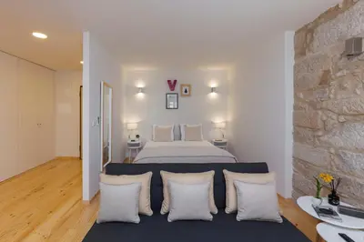 a bedroom with a bed and a stone wall at Oporto Local Studios in Porto