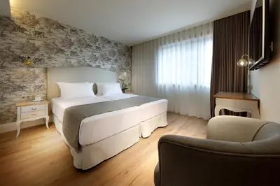 a bedroom with a large white bed and a chair at Eurostars Porto Douro in Porto