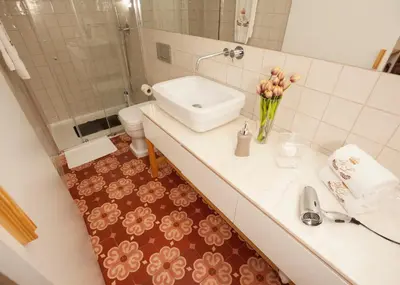 a bathroom with a toilet and a sink with a vase of flowers at ML Apartments Story in Porto