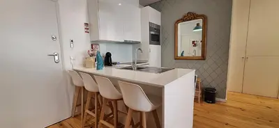 a kitchen with a bar with stools and a sink at Oporto Golden View Ribeira in Porto