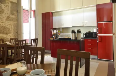 a kitchen with a red refrigerator and tables and chairs at Dukes Corner Guest House in Porto