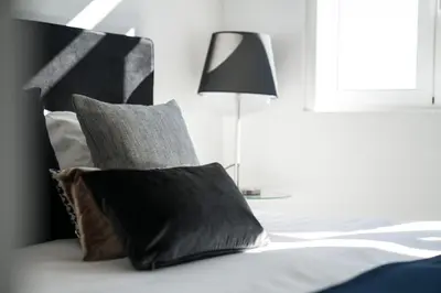 a bed with black and white pillows and a lamp at Downtown Residence by Apartments2Enjoy in Porto