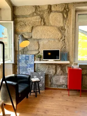 a living room with a stone wall with a black chair at Downtown Residence by Apartments2Enjoy in Porto