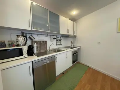 a kitchen with white cabinets and a green rug at Burgães II Apartment in Porto