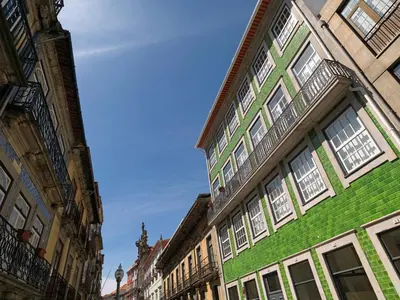 a green building with white windows on a street at FLH Porto Modern Rooftop in Porto