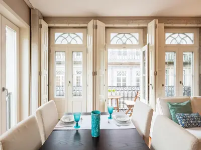 a dining room with a table and chairs and windows at Cardosas Boutique Apartment in Porto