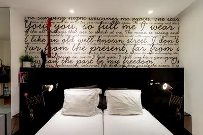 a bedroom with two beds and a large wall with writing at Porto Trindade Hotel in Porto