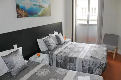 a bedroom with two beds and a chair at Lunar Guest House in Porto
