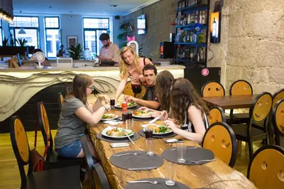 a group of people sitting at a table eating food at Nice Way Porto Hostel in Porto