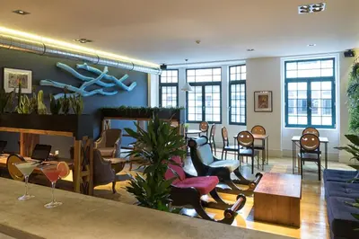 a waiting room with chairs and tables and windows at Nice Way Porto Hostel in Porto
