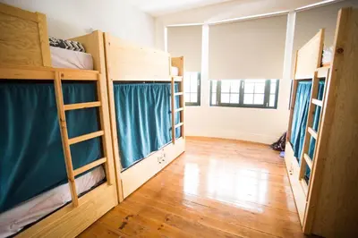 a room with three bunk beds in a room with a wooden floor at Nice Way Porto Hostel in Porto
