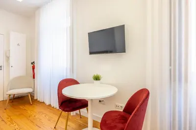 a white table with red chairs and a tv on a wall at Try Oporto - São Lázaro in Porto