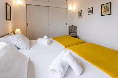 two beds in a room with white and yellow sheets at Apartamento Vintage 2 in Porto