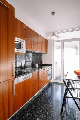 a kitchen with wooden cabinets and a sink and a table at BBA Apartments Boavista - Casa da Música with free parking in Porto