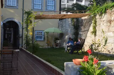 two people sitting in chairs under an umbrella in a yard at Porto.arte guest apartments in Porto