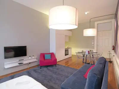 a living room with a blue couch and a red chair at New Oporto Apartments - Mouzinho in Porto