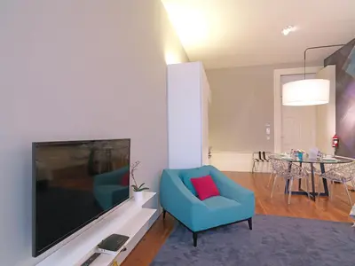 a living room with a blue chair and a tv at New Oporto Apartments - Mouzinho in Porto