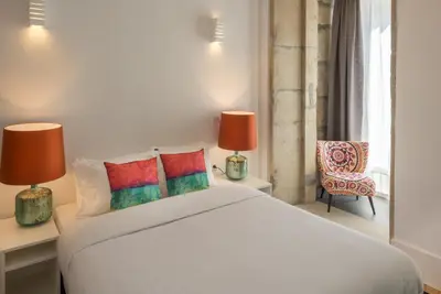 a bedroom with a white bed with two lamps and a chair at Oporto Welcome Apartments - Santa Catarina in Porto