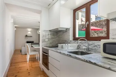 a kitchen with white cabinets and a sink at BRA.com Apartments Oporto Pinheiros in Porto