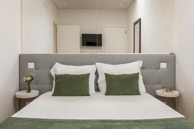 a bedroom with a large white bed with green pillows at BRA.com Apartments Oporto Pinheiros in Porto