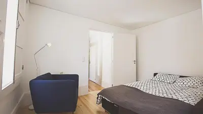 a bedroom with a bed and a blue chair at BmyGuest - Almada Garden Apartment in Porto
