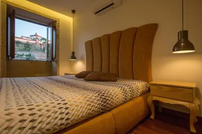 a bedroom with a bed with a large headboard and a window at GuestReady - Eiffel Waterfront apartments in Porto