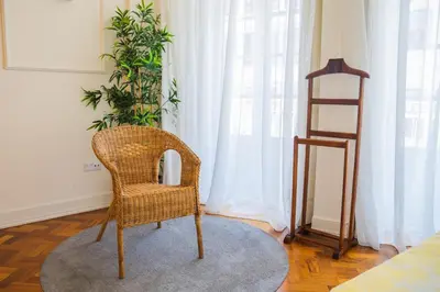 a wicker chair sitting in a room with a plant at Impar Luxury Apartments in Porto