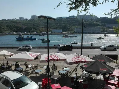 a group of tables with umbrellas and cars on the water at Porto Douro River Guest House in Porto