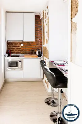 a kitchen with white cabinets and a table and a chair at Douro Riverside Apartments in Vila Nova de Gaia