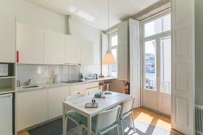 a kitchen with white cabinets and a table with chairs at Monchique´s Balcony in Porto