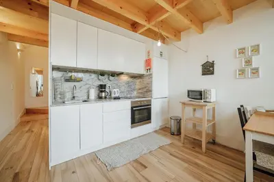 a kitchen with white cabinets and a wooden floor at Historic & Sunny Mezzanine Bolhão by Vacationy in Porto