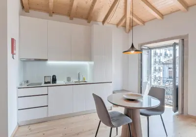 a kitchen with white cabinets and a table and chairs at Oporto Street Sá de Noronha in Porto