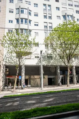 a tall white building with trees in front of a street at Avenida Apartment by MP in Vila Nova de Gaia