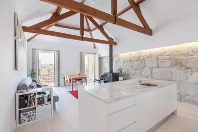 a kitchen with white cabinets and a stone wall at Boutique Rentals - Hidden Treasure in Porto