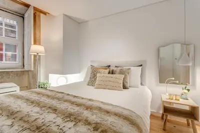 a white bedroom with a large bed and a window at Janika's Apartment in Porto
