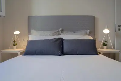 a white bed with blue pillows on top of it at Spot Apartments Ceuta in Porto