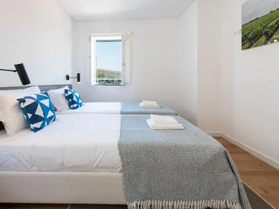 a white bedroom with a large bed with blue and white pillows at Arco Apartments in Porto