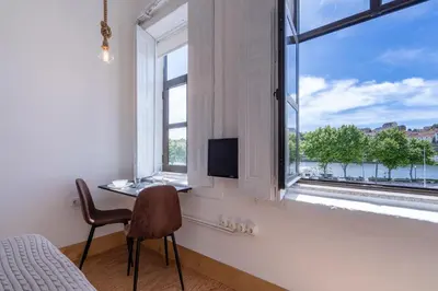 a bedroom with a chair and a desk in front of a window at Goabio Studio River View in Porto