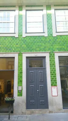 a green brick building with a blue door and windows at Flowers Center in Porto
