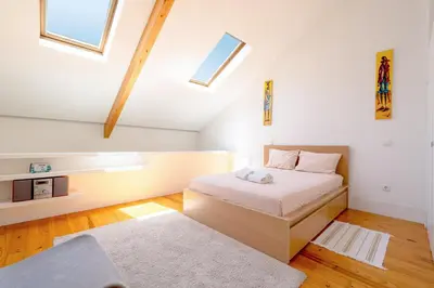 a bedroom with a bed in a room with skylights at Apartamento City Center in Porto