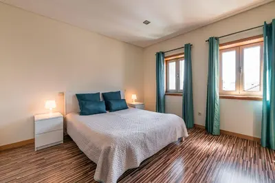 a bedroom with a bed with blue pillows and two windows at Sunrise House in Porto